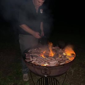 Shropshire Hills Catering night-time cooking sausages on a Kadai fire-bowl